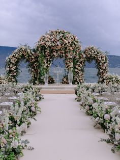 an outdoor wedding setup with flowers and greenery on the aisle, overlooking the water