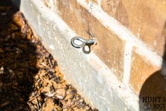 a pair of scissors hanging from the side of a brick wall next to mulch