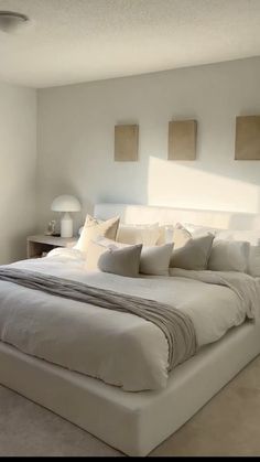 a large white bed sitting in a bedroom next to two lamps on either side of it