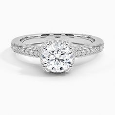 a white gold engagement ring with diamonds on the band and a round center stone in the middle