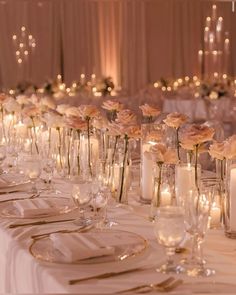 a long table is set with candles and flowers in vases for centerpieces