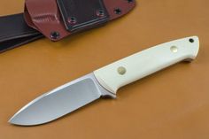 a knife sitting on top of a brown table next to a black and red sheath