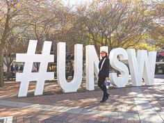 a man standing in front of a large sign with the words u s w on it