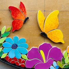 colorful flowers and butterflies are on the ground next to each other, with one flower in the center