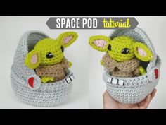 a crocheted baby yoda in a basket with the word space pod attached to it