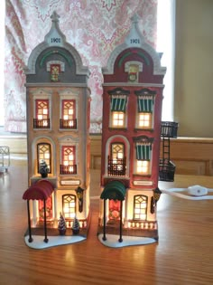 two lit up buildings sitting on top of a wooden table