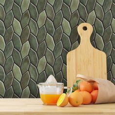 a wooden cutting board sitting on top of a table next to oranges and a cup