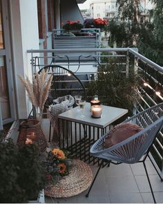 two chairs and a table on a balcony with flowers in vases next to them