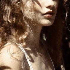 a woman with long curly hair standing in the sun