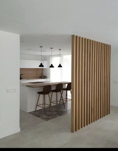 an open kitchen and dining area with wooden slats on the wall, along with bar stools