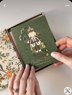 two hands are holding an open book with the cover decorated like a nutcracker