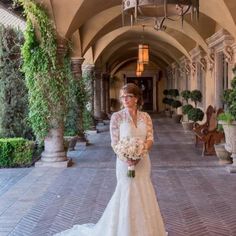 a woman in a wedding dress standing on a brick walkway with greenery and potted plants