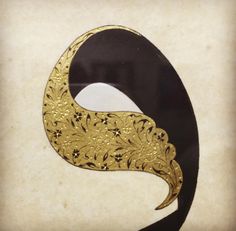 a black and gold masquerade mask with flowers on it's side, in front of a beige background