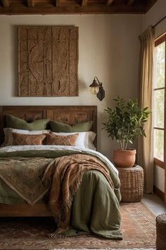 a bedroom with a large bed covered in green blankets and pillows next to a potted plant