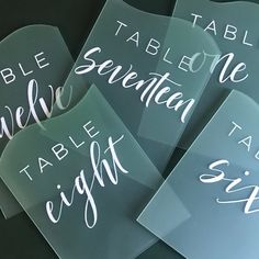 four place cards with white calligraphy on them are sitting next to each other in front of a black background