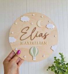 a person holding up a wooden sign with the name elis maximumian on it