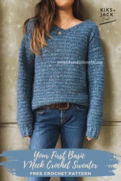 a woman standing in front of a wall wearing a blue sweater