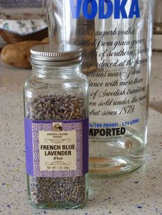 a bottle of vodka next to a glass jar filled with lavender