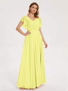 a woman in a long yellow dress standing with her hands on her hips and looking at the camera