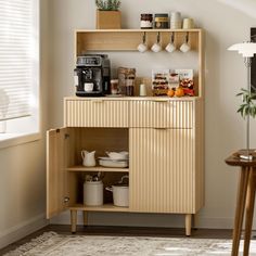 a small kitchen with a wooden cabinet and coffee maker on the counter, in front of a window