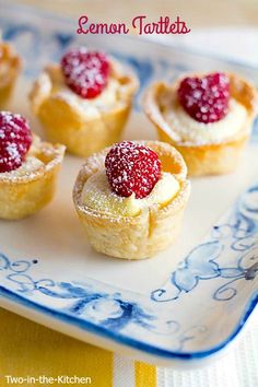 small pastries with raspberries are on a blue and white plate