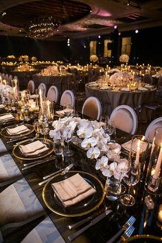 the tables are set with black and white linens, gold chargers, silverware, and candles