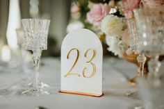 the table is set with wine glasses, champagne flutes and an elegant number 23 sign