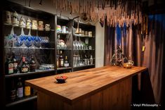 a wooden counter top sitting in front of a shelf filled with bottles