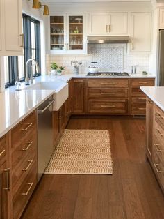 a kitchen with wooden cabinets and white counter tops, along with a rug on the floor