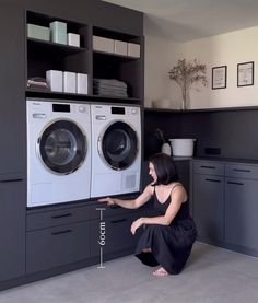 a woman kneeling down in front of a washer and dryer