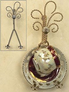 an antique tea cup and saucer is hanging from a chain on a white wall