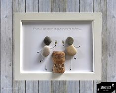 two rocks and a cork are placed in a white frame on a wooden background with words written below them