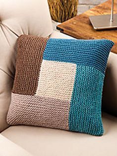 a white chair with a blue and brown knitted pillow on it's back