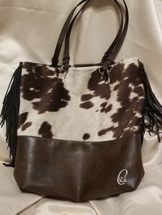 The Brown Cow bag is 13" wide, 15 1/2" tall and 4" deep (front to back) with brown tassels on the side. It is a faux cow hide and faux leather. Lined with linen and 2 interior pockets. Faux Cowhide, Home Id, Brown Cow, Mountain Home, Cow Hide, Tote Bag Purse, Laptop Bag, Tote Bags, Tassels