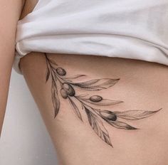 an olive branch tattoo on the side of a woman's stomach is shown in black and white