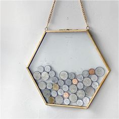 a hexagonal display case filled with coins hanging on a gold plated chain