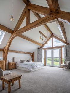 a large bedroom with wooden beams and white walls, carpeted flooring and furniture