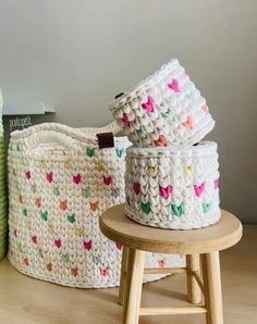 three crocheted baskets sitting on top of a wooden stool next to each other