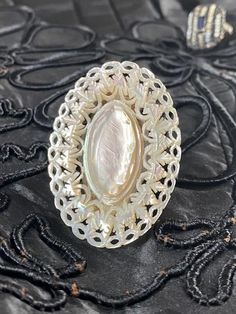 Singkiang one of a kind designed Edwardian mother of pearl carved button mounted by bonding onto a sterling silver ring. Measures 2: H x 1.5" W finger size is approx 10. White Oval Brooch Jewelry, Unique Mother Of Pearl Shell Jewelry, Unique Shell-shaped Mother Of Pearl Jewelry, Elegant Mother Of Pearl Round Rings, Wedding Pearl Ring In Mother Of Pearl, Wedding Pearl Ring With Mother Of Pearl, Elegant Carved White Rings, Elegant White Carved Rings, Unique Mother Of Pearl Jewelry For Wedding