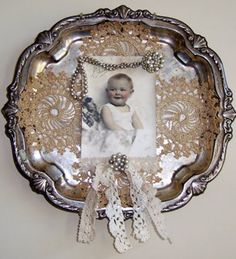 an ornate silver plate with a photo on the front and white lace trim around it