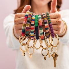 a woman is holding several bracelets with keys in her hands and giving the thumbs up sign