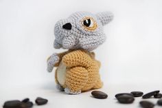 a crocheted stuffed animal sitting on top of some black rocks