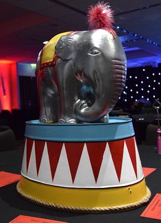 an elephant statue sitting on top of a circus ring with red and yellow decorations around it