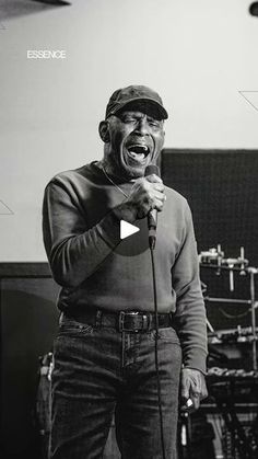 a man singing into a microphone while standing in front of a drum set and recording equipment