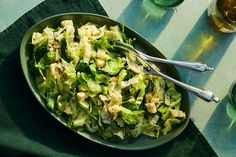 a bowl filled with lettuce and other vegetables next to two glasses of beer