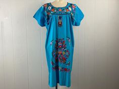 Vintage 1970s dress or tunic. Pull over style. Made of blue cotton with multi colored embroidered birds and flowers. Bohemian ethnic design, maybe Mexican or South American.  No label. About a size large.   Actual measurements are: 51" at the bust 50" at the waist 52" at the hips 24" shoulder seam to shoulder seam 46" overall length In very good condition. Vintage Blue Embroidered Dresses, Folk Style Blue Festival Dress, Blue Folk Style Festival Dress, Blue Folk Style Short Sleeve Dress, Folk Style Blue Short Sleeve Dress, Blue Short Sleeve Folk Dress, Blue Folk Dress With Short Sleeves, Folk Style Blue Embroidered Beach Dress, Folk Style Blue Embroidered Dress For Beach