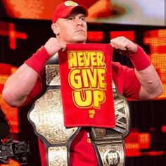 the man is holding up a red shirt that says never give up in front of him