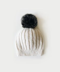 a white knitted hat with a black pom - pom