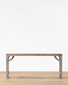 a wooden bench sitting on top of a hard wood floor next to a white wall