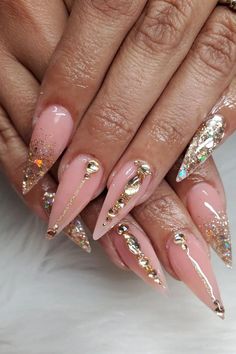 Elevate your nail game with these stunning stiletto-shaped nails boasting a perfect blend of subtlety and glamour. A delicate pink base provides a soft canvas, complemented by a sprinkle of multicolored glitter adding a touch of sparkle. Select nails are enhanced with exquisite gold chain accents draped elegantly, along with tiny gold rhinestones that provide an opulent finish. These nails are a true testament to sophistication meeting a sparkle of luxury. ✨  // Photo Credit: Instagram @marlett8a Mixed Nail Shapes, Gold Gem Nail Designs, Nails Pink And Gold, Pink Nails With Gold Gems, Celebration Nails, Nude Diamond Nails, Gold Stiletto Nails Designs, Dope Nail Designs Fall 2024, Pink And Gold Nail Designs